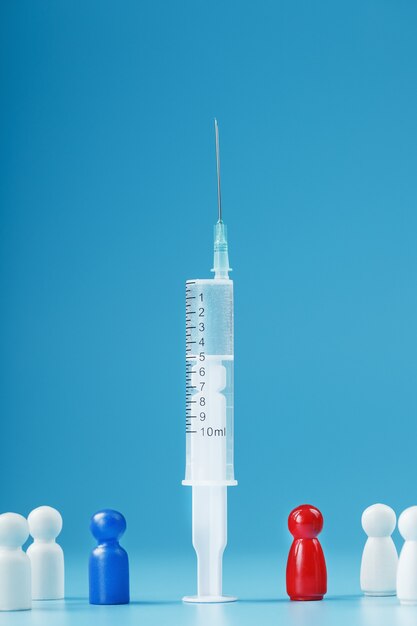 青の背景に白人の群衆と青と赤の男と中央にワクチンの注射器。