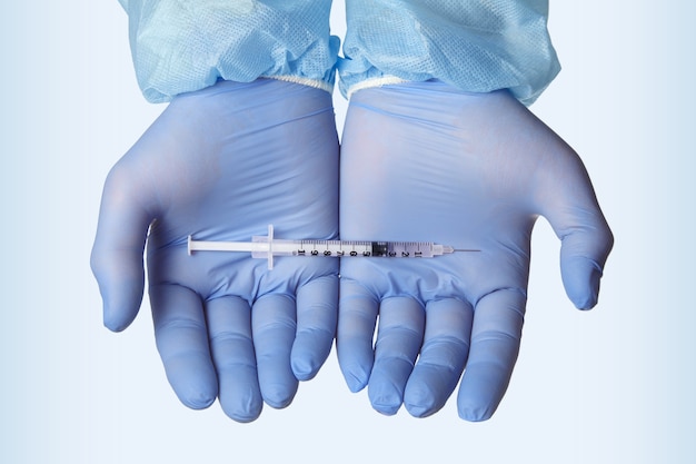 Syringe with a vaccine on hands in latex blue gloves. Creation of a vaccine against viruses