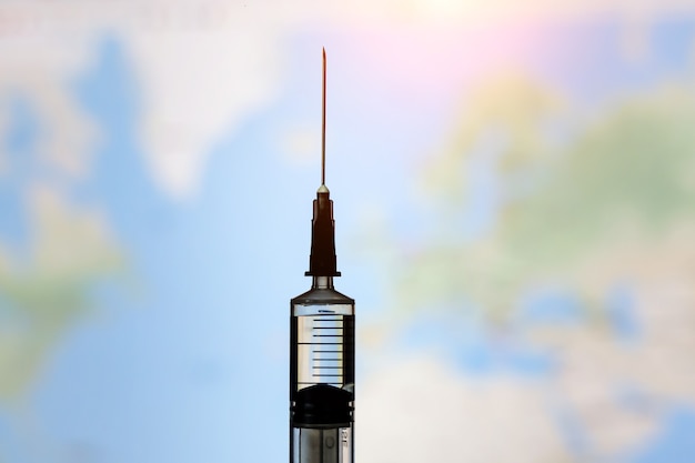 Syringe with vaccine on world map