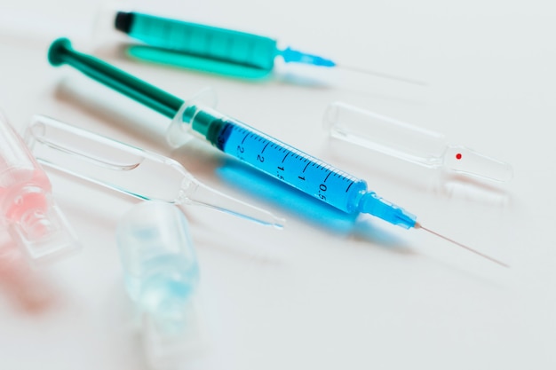 syringes and ampoules with multicolored liquid on white.