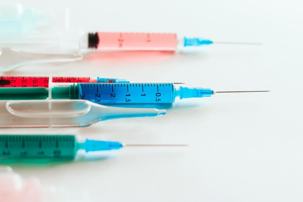 syringes and ampoules with multicolored liquid on white