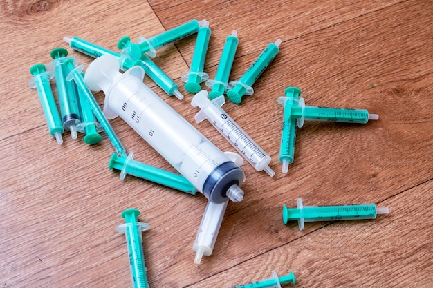 Syringes scattered on the wooden floor closeup