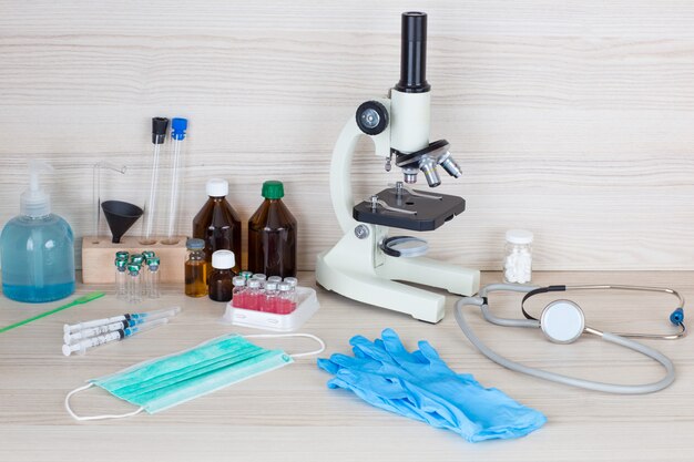 syringes, vaccines, microscope, stethoscope on the table (chemical laboratory)