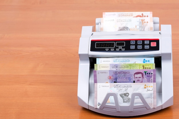 Syrisch geld in een telmachine op houten tafel