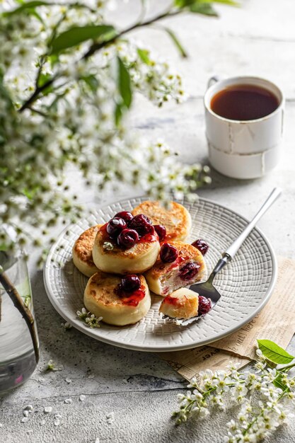 シルニキの伝統的なロシアのチーズパンケーキをチェリーと一緒に朝食に提供