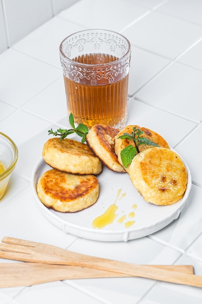 syrniki with honey on a white plate