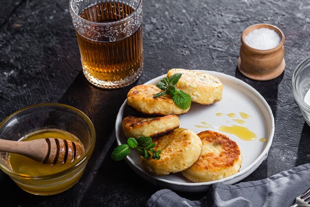 syrniki with honey on a white plate