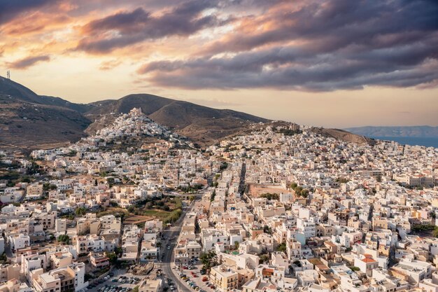 Syros eiland Griekenland lucht drone view Ermoupolis en Ano Siros stad stadsbeeld bewolkte hemel bij zonsondergang