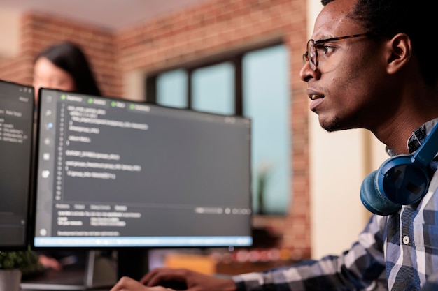 System engineer typing machine learning server code on computer, sitting at desk in software company. Programming engineer working on database system with coding script in it security agency.