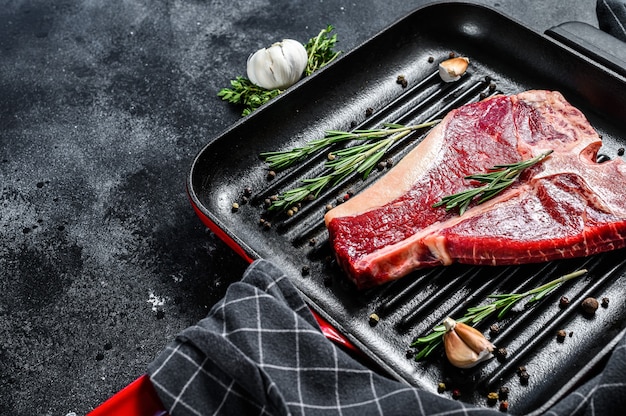 T-bone steak in een pan. Biologisch rauw Tbon-rundvlees. Zwarte achtergrond. Bovenaanzicht. Kopieer ruimte.