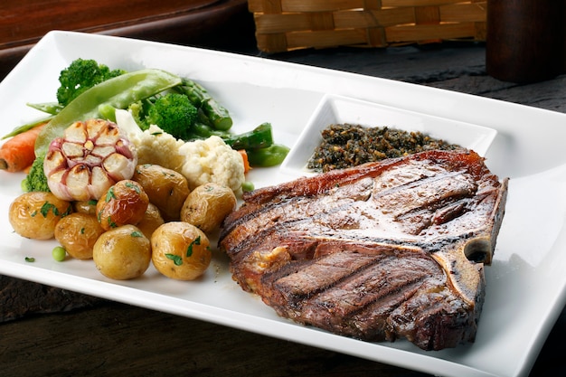 T bone steak with potato salad and vegetables