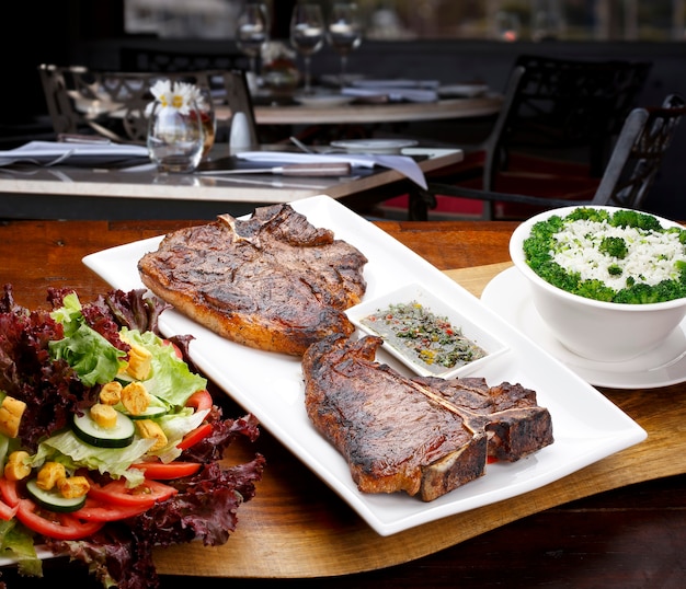 T bone steak with potato salad and vegetables