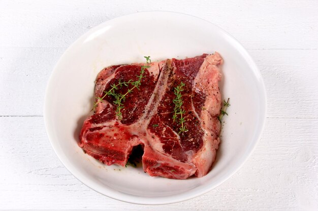 T-bone steak with spices on a white background