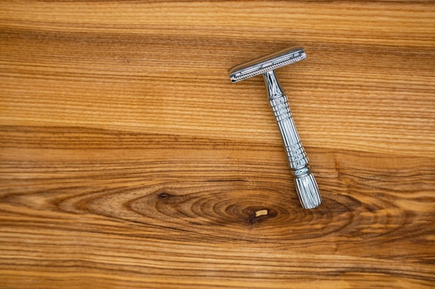 T-shaped razor on a wooden table. Top view