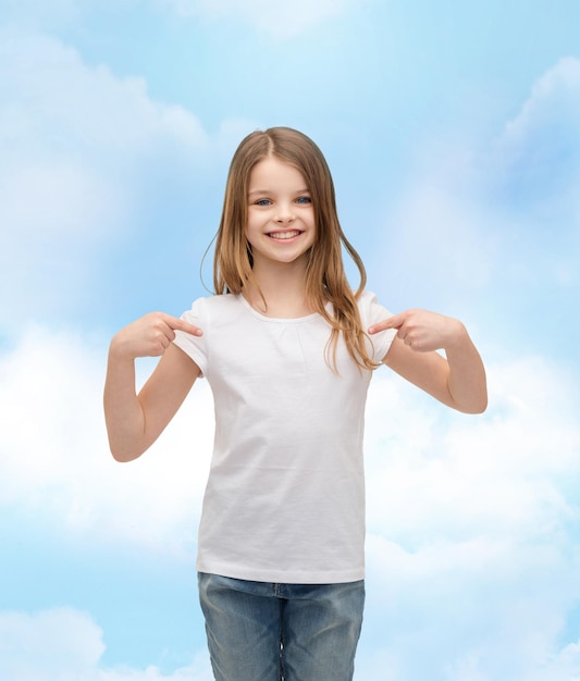 티셔츠 디자인 개념 - 자신을 가리키는 흰색 티셔츠를 입은 웃는 어린 소녀