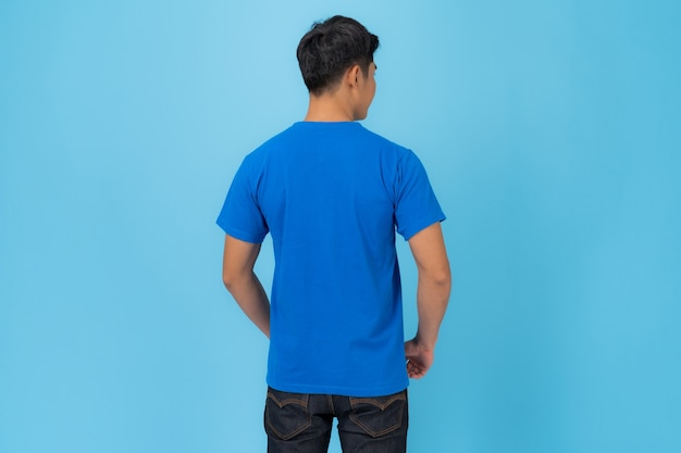 Design t-shirt, giovane uomo in maglietta blu isolato su sfondo blu