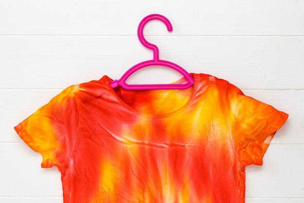 T-shirt in tie-dye-stijl in gele en rode kleuren op een witte tafel