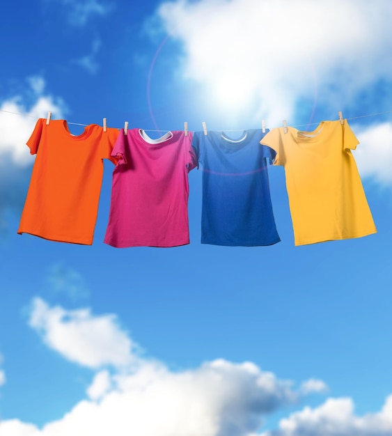 T-shirts hangen aan een waslijn voor blauwe lucht en zon
