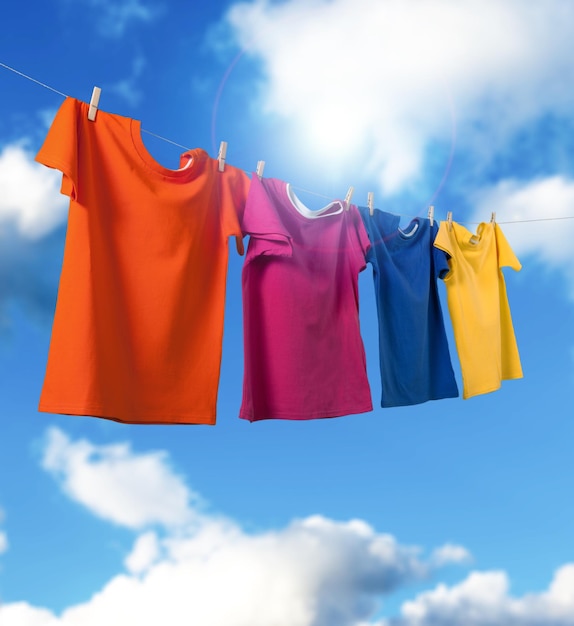 T-shirts hanging on a clothesline in front of blue sky and sun