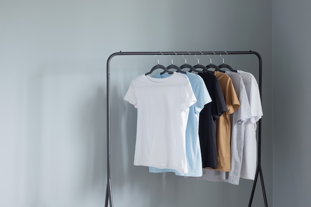 T-shirts van neutrale kleuren op zwarte hanger tegen grijze muur