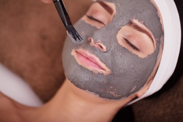 t Young woman with nutrient facial mask in beauty salon