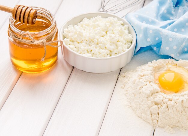 Taart bakken in rustieke keuken - deeg recept ingrediënten eieren, bloem, melk, boter, honing op witte planken houten tafel van bovenaf