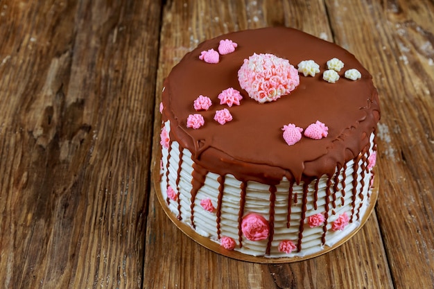 Taart bedekt met chocolade met roze rozen op het oude bord