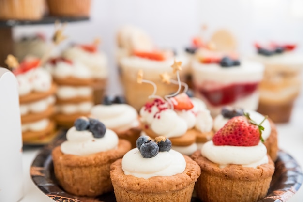 Taart met verschillende bessen en schuimgebakjes. Cakes, dessert met bessen, candybar voor feest. Heerlijke snoepjes op snoepbuffet. Gelukkige verjaardag-bar