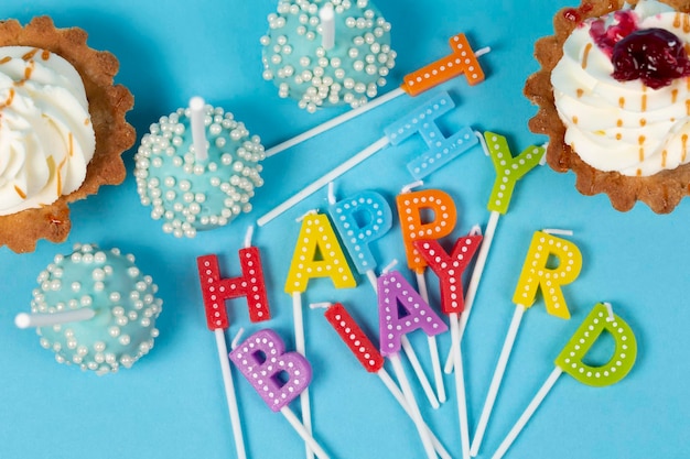 Taarten en cupcakes met regenboogkleurige verjaardagskaarsen met de tekst Happy Birthday