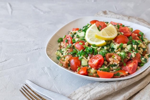 Foto insalata tabbouleh su un piatto su uno sfondo di cemento grigio chiaro cucina libanese