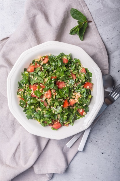 Tabbouleh salad, traditional middle eastern or arab dish. Usually prepared with parsley, mint, bulgur, tomato. Concrete rustic background