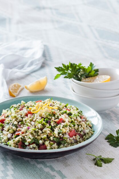 Photo tabbouleh salad. traditional middle eastern or arab vegetarian salad with bulgur, parsley, mint and tomato. copy space