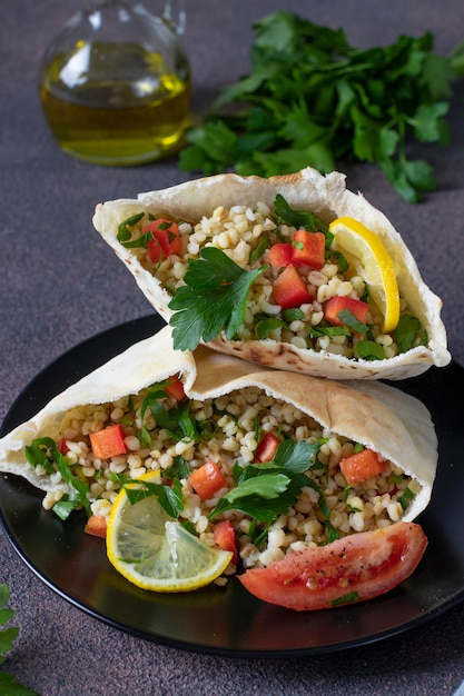 Insalata di tabbouleh con bulgur e prezzemolo in pita su piatto scuro primo piano cucina mediorientale