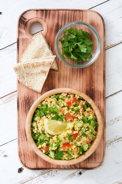 Tabbouleh salad with couscous in bowl on rustic white table top view