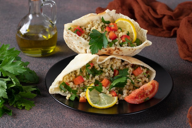 Foto tabbouleh salade met bulgur en peterselie in pita op een donkere plaat midden-oosterse keuken