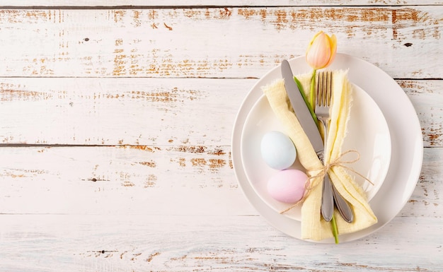 Tabel instelling voor paasfeest paaseieren tulpen en bestek bovenaanzicht plat lag op witte rustieke achtergrond