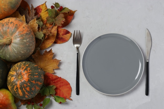 Tabel op Thanksgiving Day ingericht pompoen en kleurrijke bladeren op grijs oppervlak