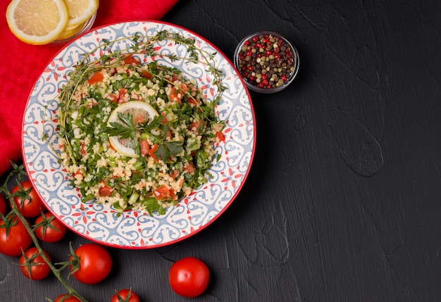 Tabelsalade op een zwarte achtergrond naast de ingrediënten.