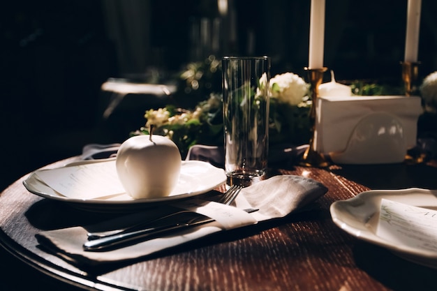 結婚式のためのテーブルの予定。ホワイトチョコレートのリンゴ。白い皿の上のメニューカード。白いリンゴ。木製のテーブルの料理。テーブルトップビューを提供しています。素朴な結婚式のテーブル