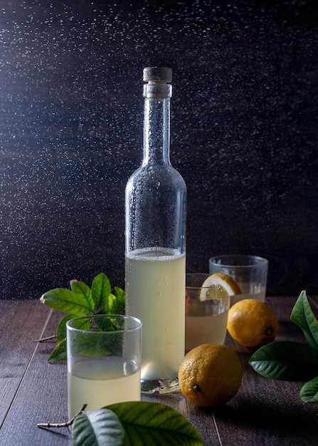 On the table are a bottle of lemon juice, glasses and a lemon.