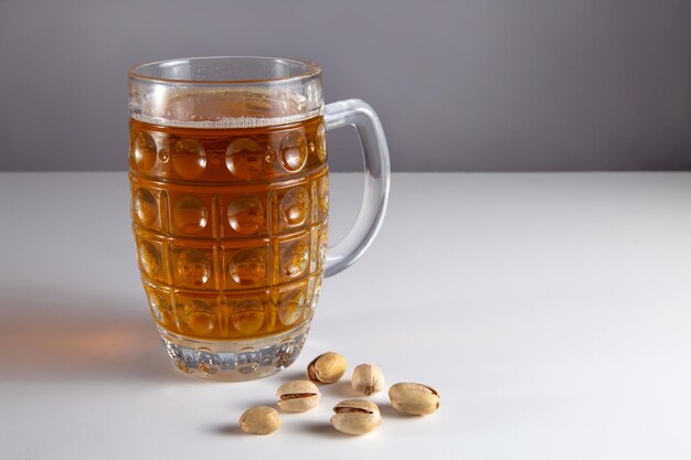 On the table are a glass of beer beer and nuts. Horizontal frame.