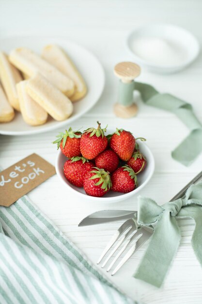 On the table are kitchen utensils and a plate with a fresh harvest strawberries a plate with Savo