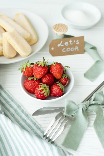 On the table are kitchen utensils and a plate with a fresh harvest strawberries a plate with Savo