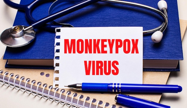 Sul tavolo ci sono dei taccuini, uno stetoscopio, una penna e un foglio di carta con il testo monkeypox virus concetto medico