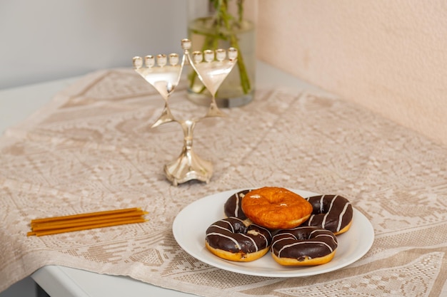 On the table are a plate of donuts, candles and Hanukkah preparation for Hanukkah.