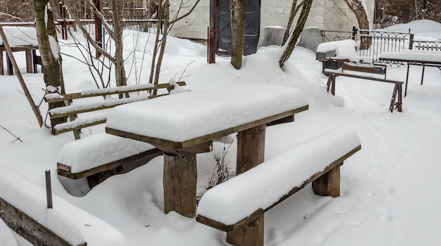 Стол и скамейки зимой под снегом.