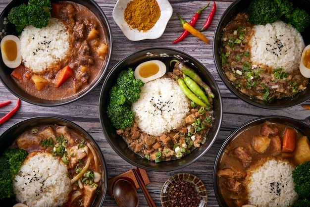 A table of bowls of food including beef and rice.