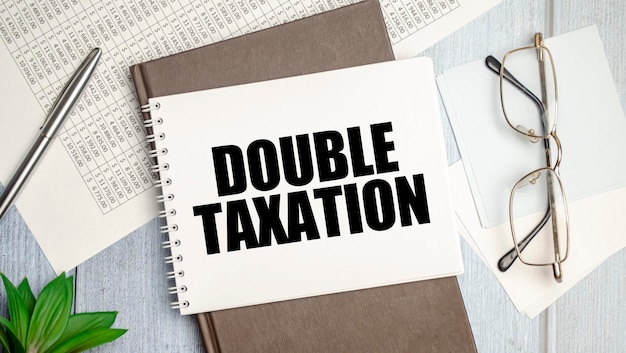 On the table charts calculator and notebook with the inscription DOUBLE TAXATION