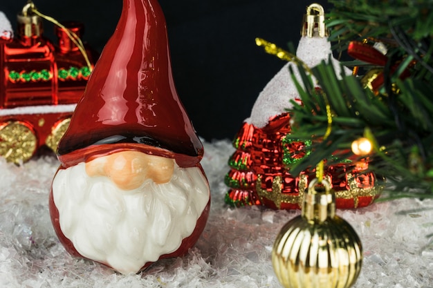 Table covered with snowflakes with Christmas decorations. Santa Claus, Christmas tree with red, gold balls and lights. Selective focus.