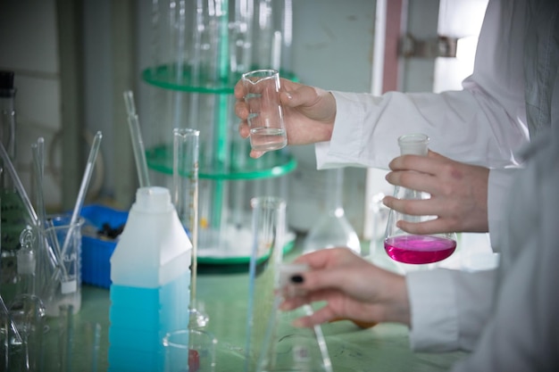 Table full of chemicals and flasks chemical lab hands holding flasks